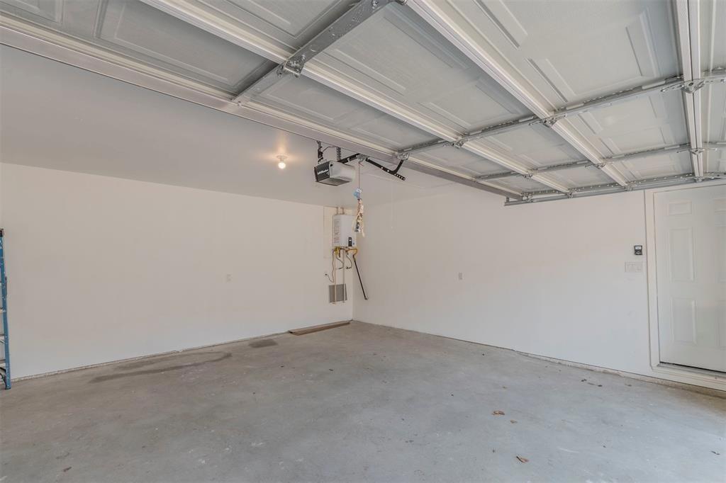 3619 Merrell Road Dallas, TX 75229 - Photo 26 of 26 Spacious garage with concrete flooring, painted walls, an overhead light fixture, and a water heater