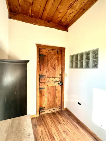 a view of a hallway with wooden floor and a bathroom