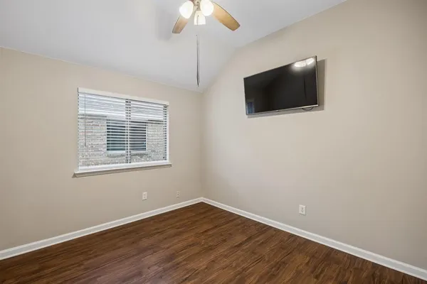 an empty room with wooden floor fan and window