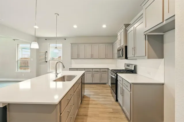 a large kitchen with stainless steel appliances granite countertop a sink a stove and a refrigerator