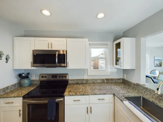 a kitchen with granite countertop a sink stainless steel appliances and white cabinets