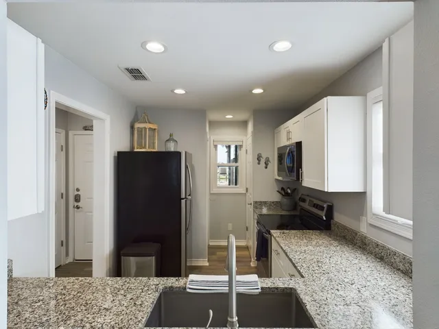 a living room with stainless steel appliances kitchen island granite countertop furniture and a rug