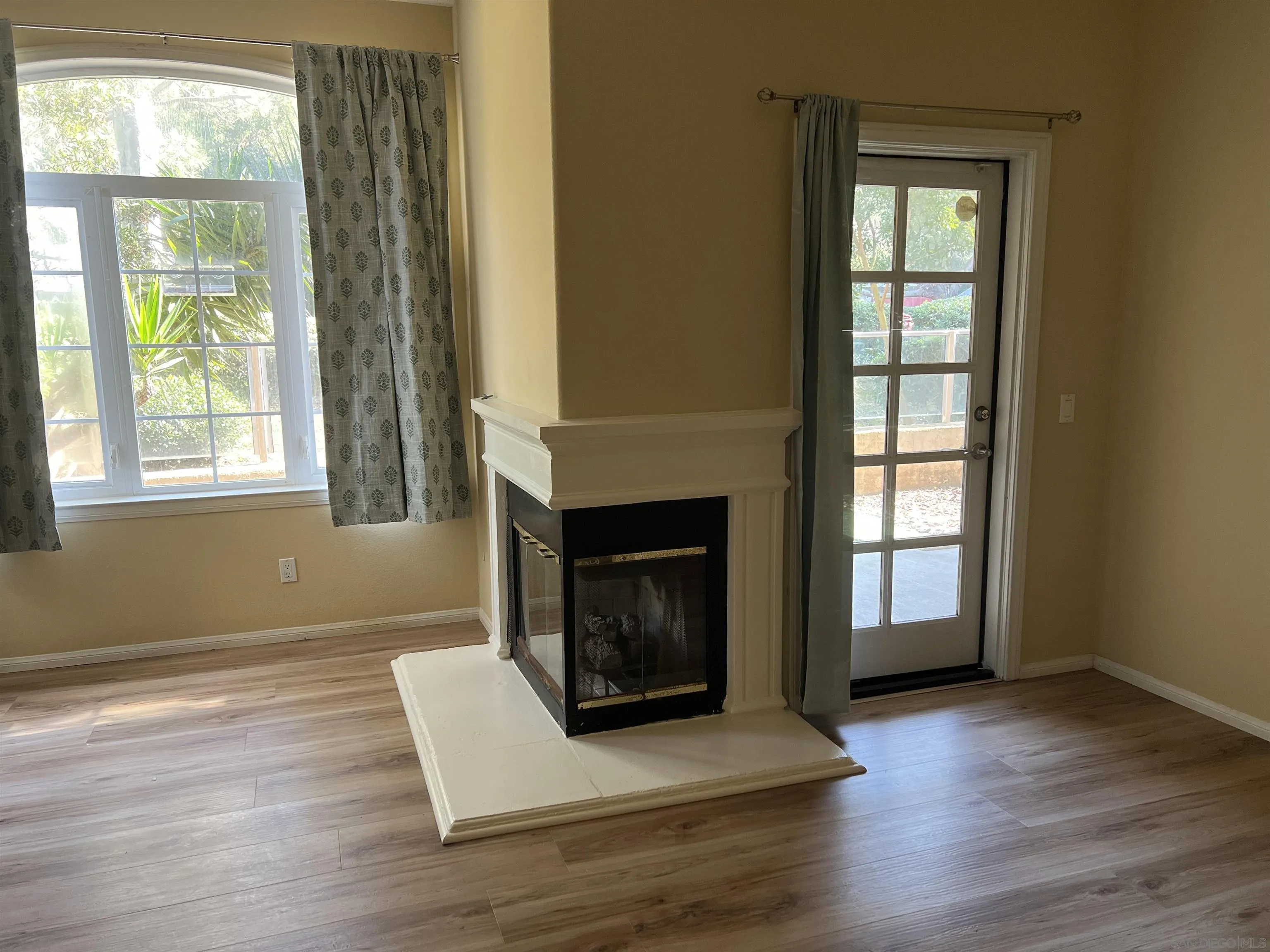 2834 Torrey Pines Road La Jolla, CA 92037 - Photo 9 of 15 an empty room with wooden floor fireplace and windows