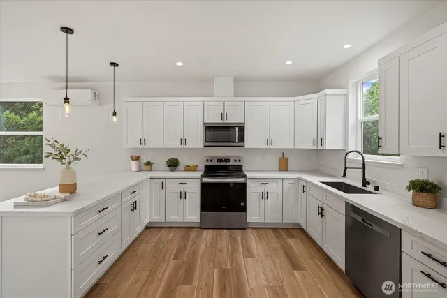 a large white kitchen with stainless steel appliances granite countertop lots of white cabinets a stove and sink