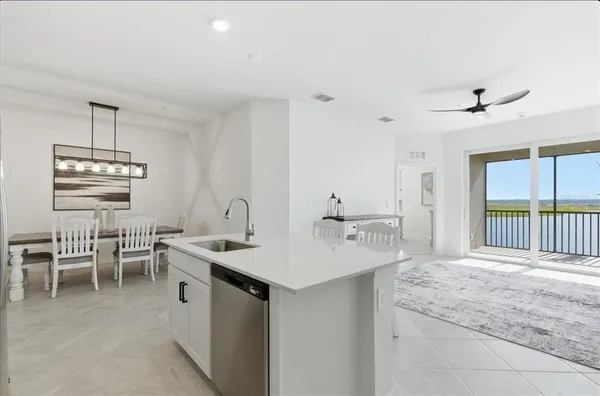 a dining hall with stainless steel appliances kitchen island a table and chairs