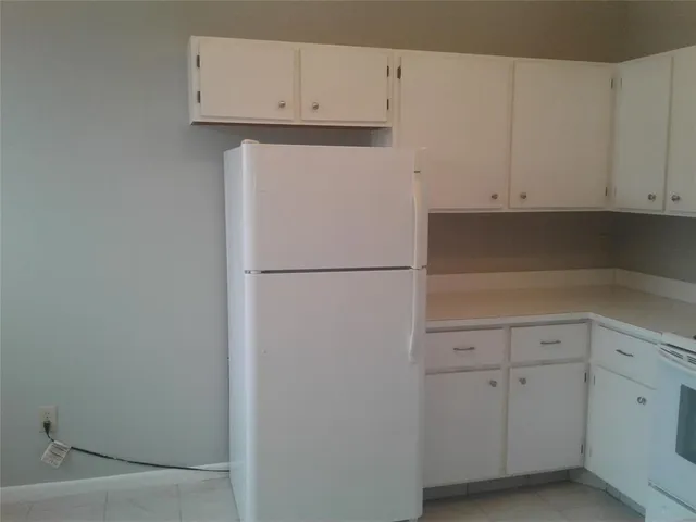 a kitchen with white cabinets and a refrigerator