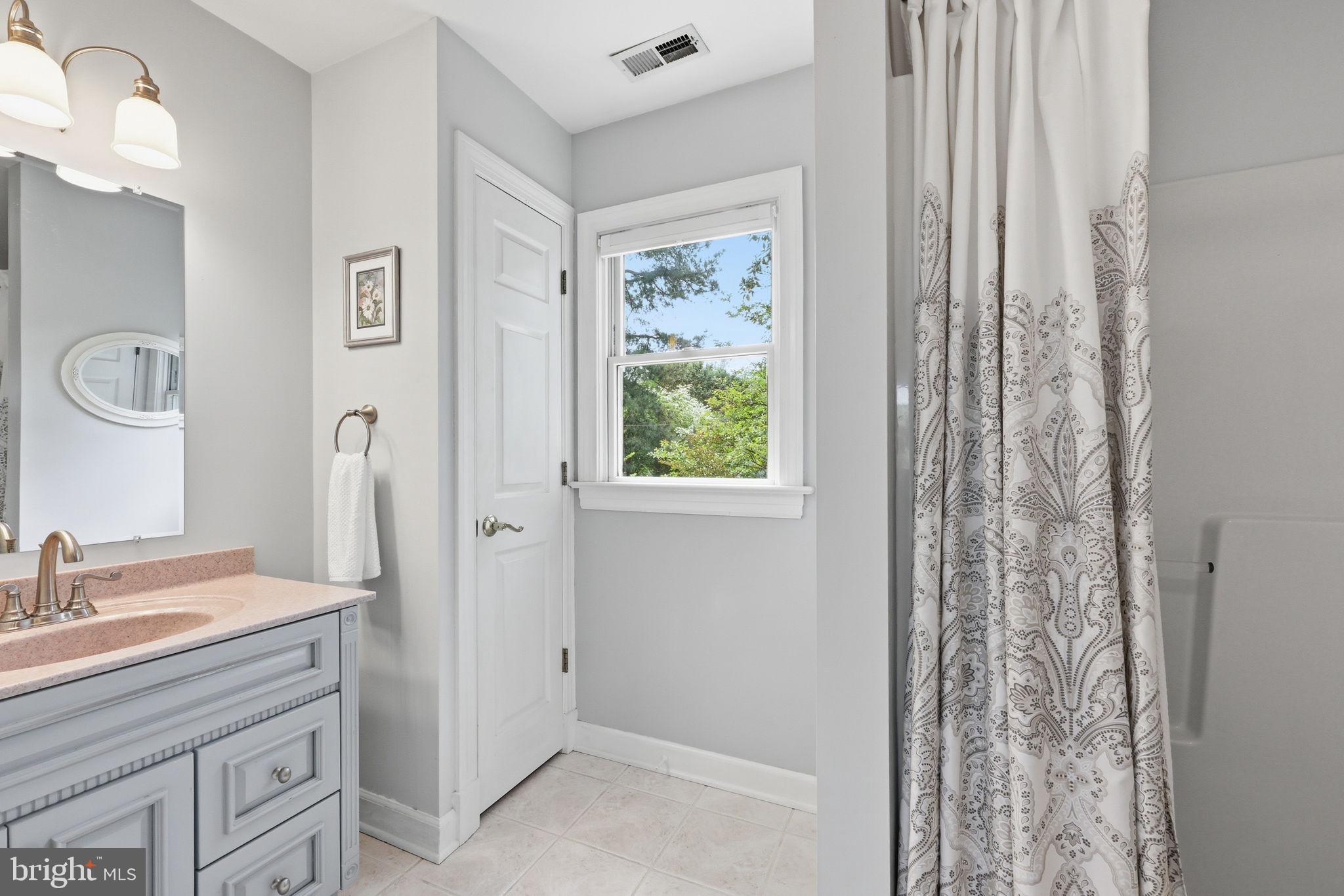 7601 Hollins Road Henrico, VA 23229 - Photo 15 of 47 a bathroom with a sink a mirror and a shower