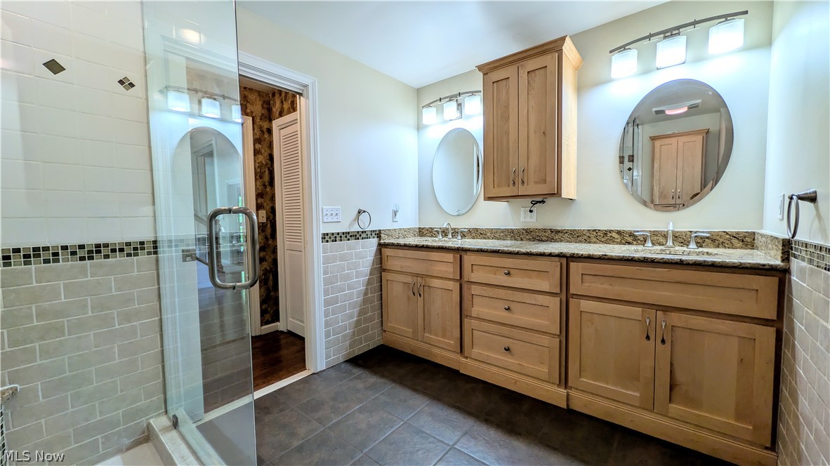 6409 Old Woods Road Ashtabula, OH 44004 - Photo 21 of 43 Bathroom featuring a dual vanity with light wood cabinetry, granite countertops, and two round mirrors