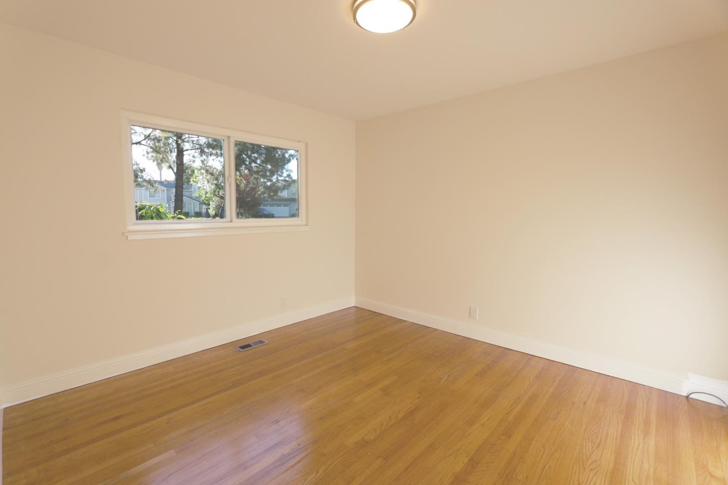 1104 Phyllis Avenue Mountain View, CA 94040 - Photo 6 of 12 an empty room with wooden floor and windows
