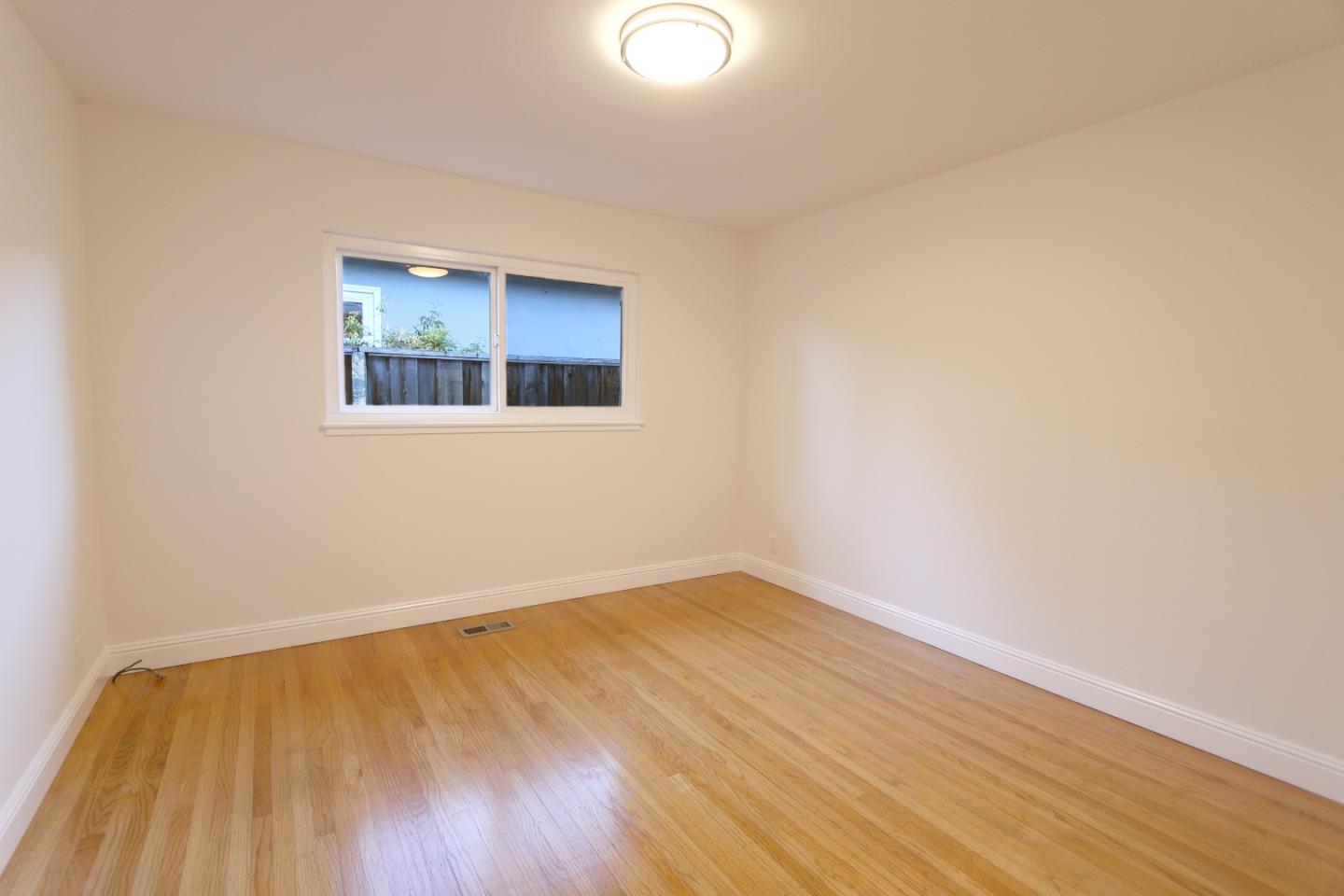 1104 Phyllis Avenue Mountain View, CA 94040 - Photo 7 of 12 an empty room with wooden floor and windows