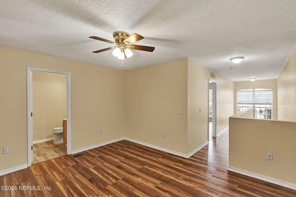 a view of empty room with wooden floor and fan
