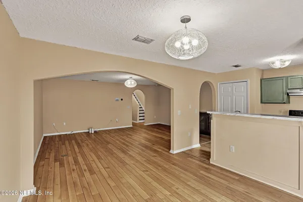 a view of an empty room with wooden floor and a large window