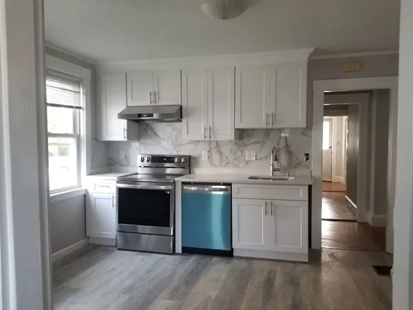 a kitchen with stainless steel appliances granite countertop a stove a sink and white cabinets