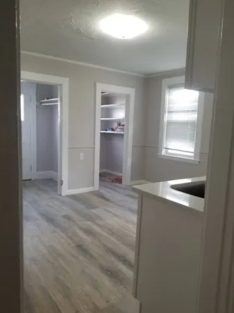 a view of empty room with window and wooden floor