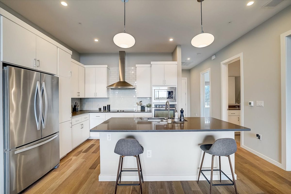 5921 Hiline Road, Unit 1204 Austin, TX 78734 - Photo 14 of 36 Kitchen with stainless steel appliances, a kitchen bar, a kitchen island with sink, wall chimney exhaust hood, and recessed lighting