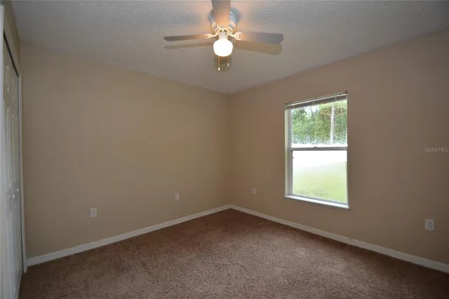 an empty room with a window and a fan