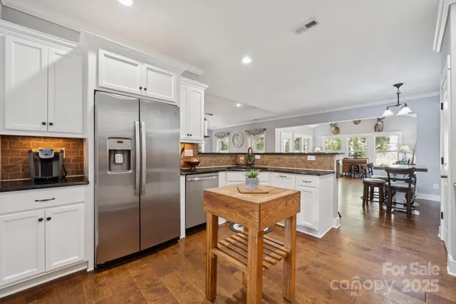 a kitchen with stainless steel appliances a refrigerator a sink a stove and white cabinets