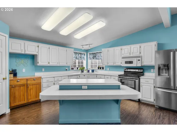 a kitchen with stainless steel appliances granite countertop a sink a stove a refrigerator a center island and cabinets