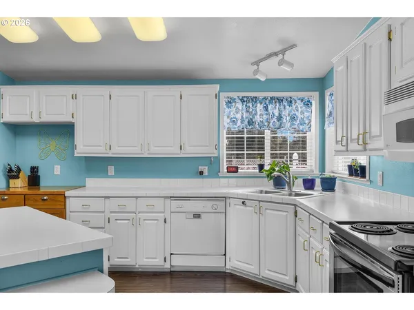 a kitchen with granite countertop a stove a sink and white cabinets