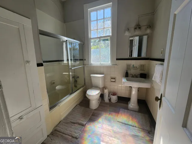 a bathroom with a toilet sink a mirror and shower
