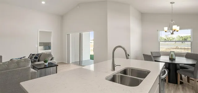 a kitchen with a sink dishwasher a stove and a dining table with wooden floor