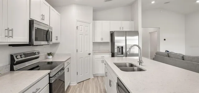 a kitchen with stainless steel appliances a sink a stove and a refrigerator with wooden floor