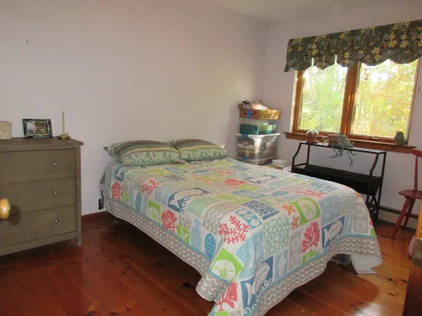 a bedroom with a bed a dresser next to a window