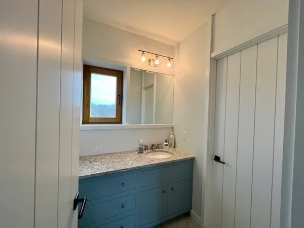 a bathroom with a granite countertop sink and a mirror