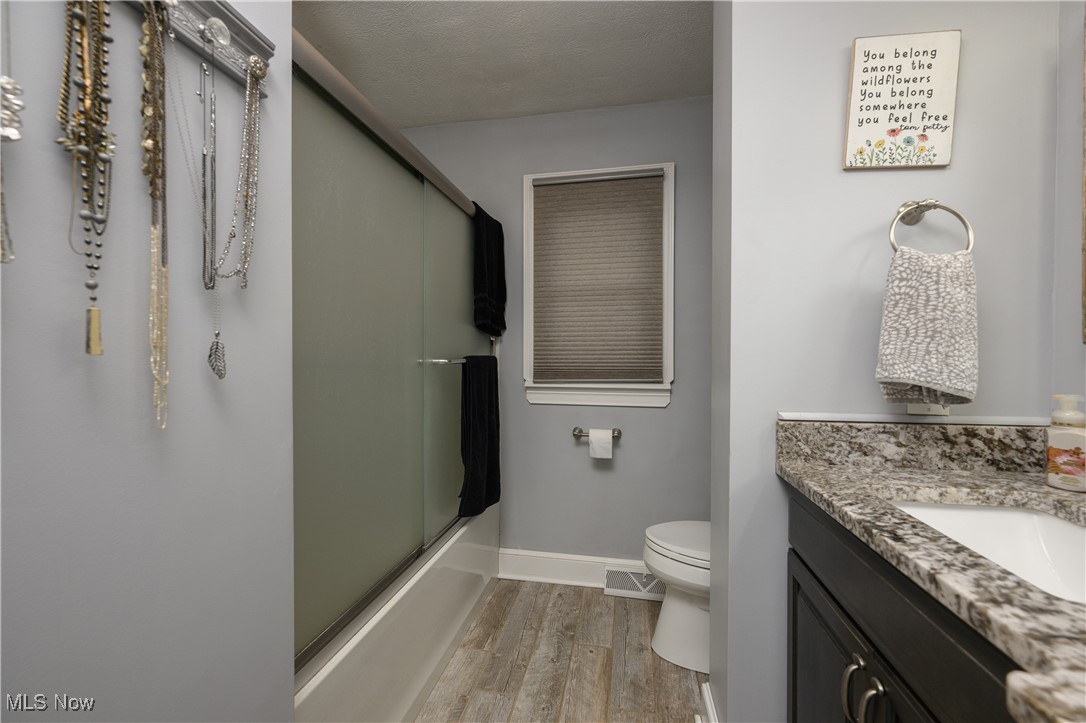 2856 Shellhart Road Barberton, OH 44203 - Photo 23 of 27 Full bathroom with wood finished floors, vanity, and bath / shower combo with glass door