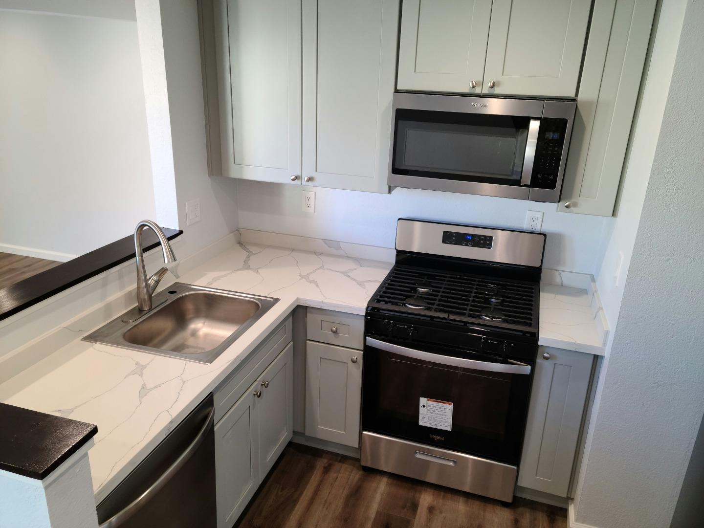 a kitchen with granite countertop white cabinets and stainless steel appliances