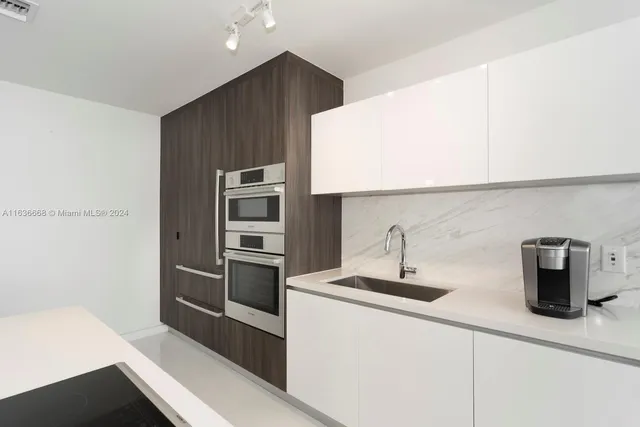 a kitchen with a refrigerator and white cabinets