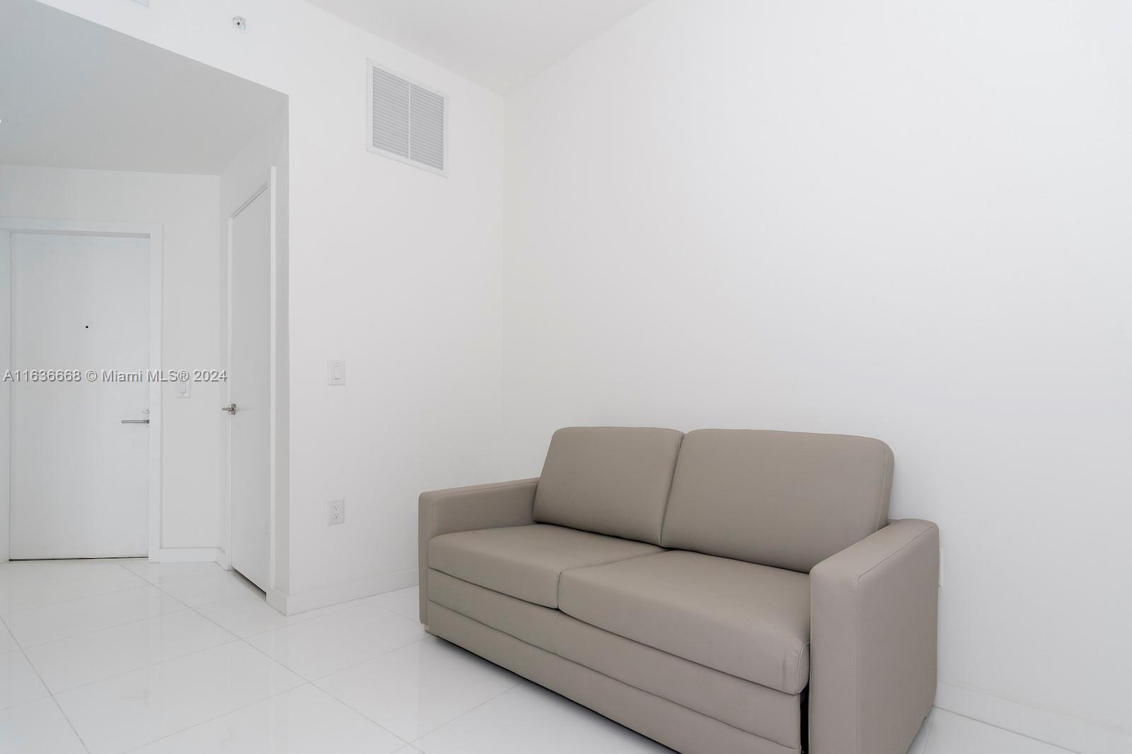 851 Northeast 1st Avenue, Unit 1710 Miami, FL 33132 - Photo 24 of 26 a blue couch sitting next to a white wall