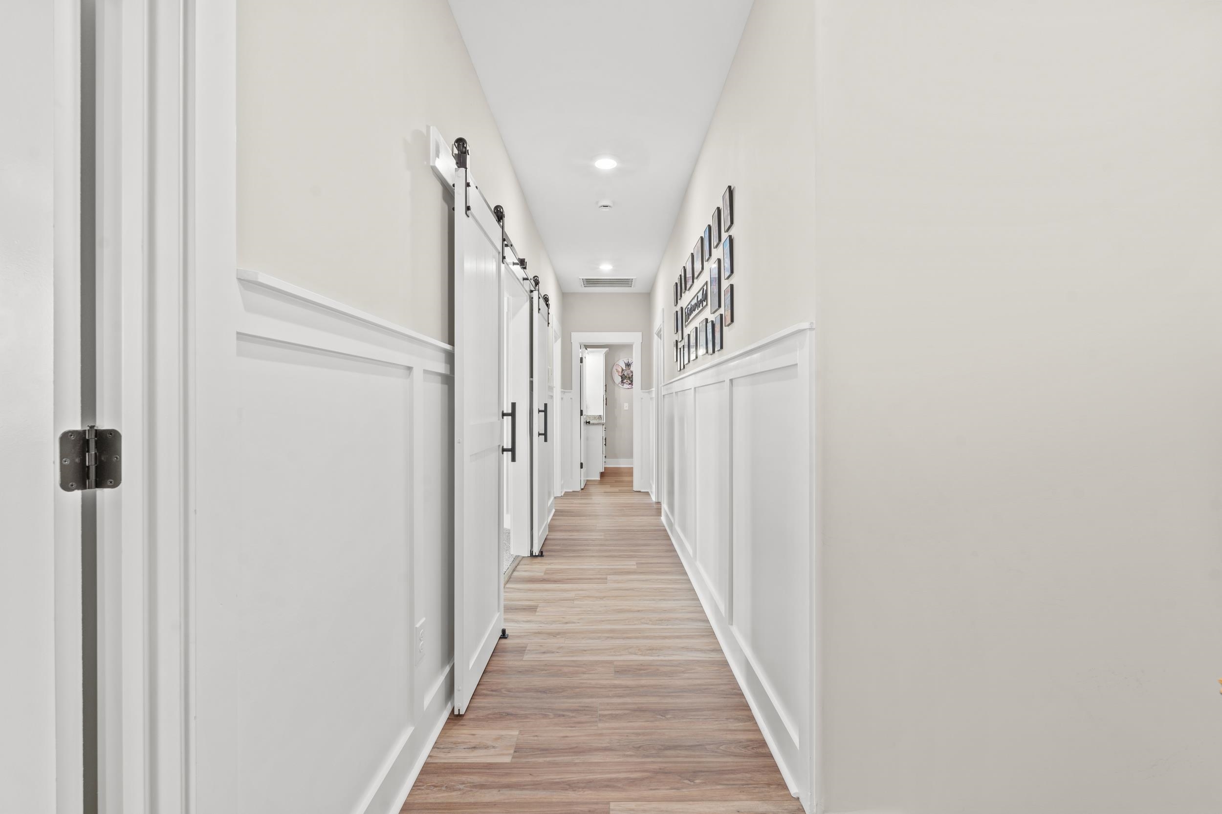 411 Chamberlin Road Myrtle Beach, SC 29588 - Photo 15 of 40 Hallway with light wood-style flooring, a barn door, recessed lighting, and a decorative wall