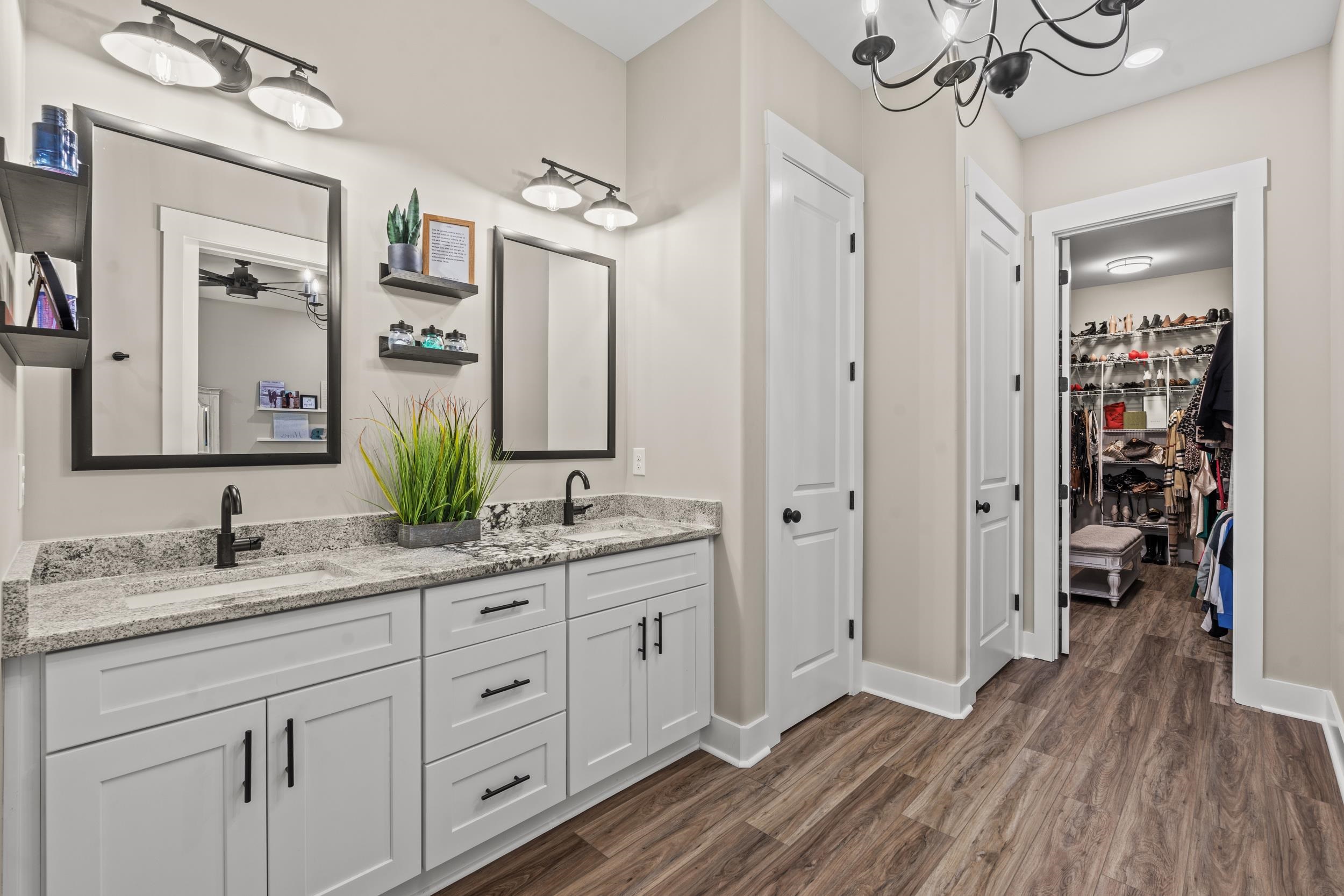 411 Chamberlin Road Myrtle Beach, SC 29588 - Photo 20 of 40 Bathroom featuring double vanity, a walk in closet, dark wood finished floors, and a chandelier