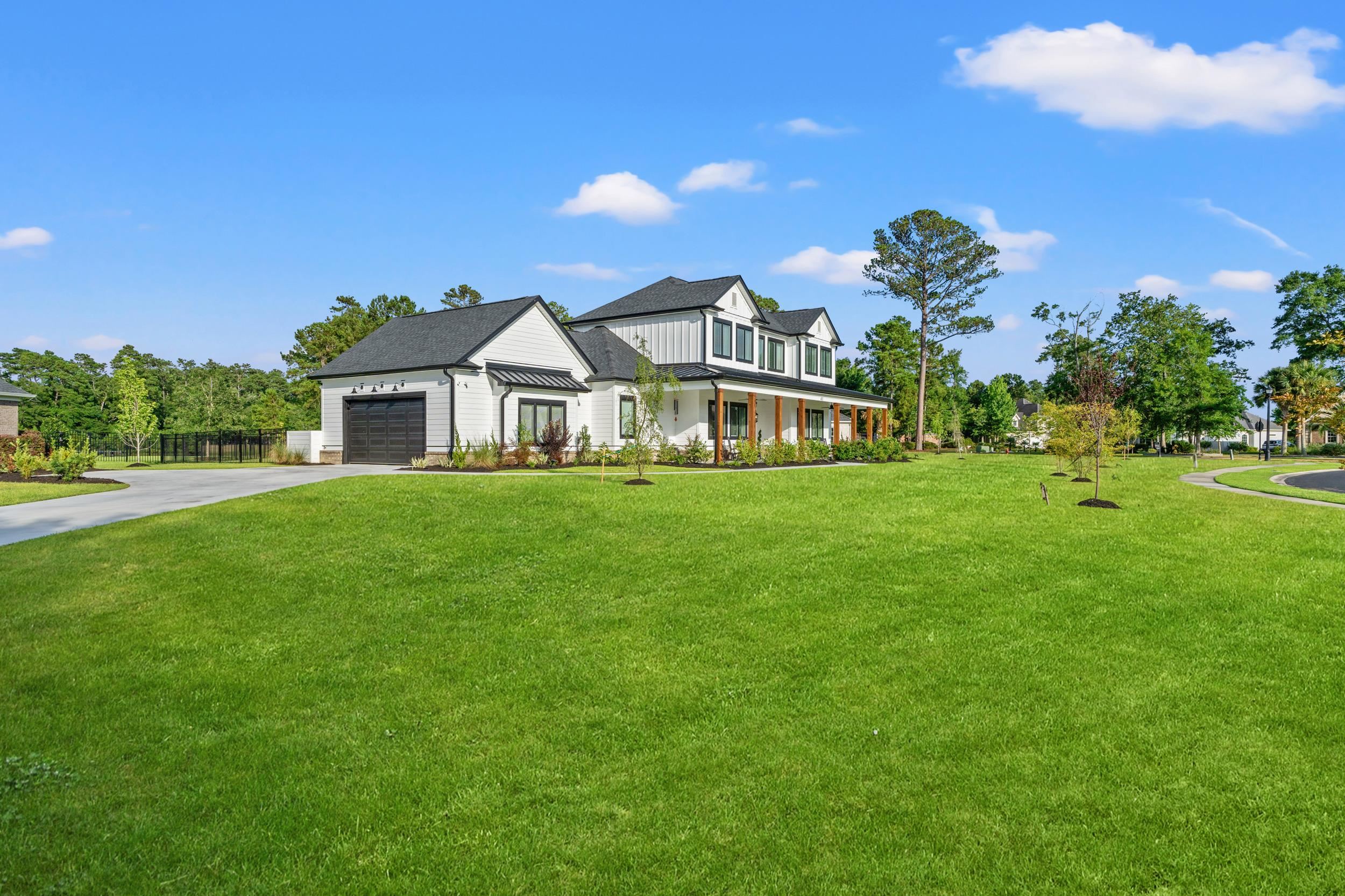 411 Chamberlin Road Myrtle Beach, SC 29588 - Photo 33 of 40 Modern inspired farmhouse with a front lawn, driveway, covered porch, an attached garage, and a shingled roof