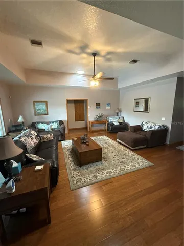 a living room with furniture kitchen view and a wooden floor
