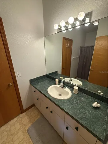 a bathroom with a granite countertop sink a light fixture and a mirror