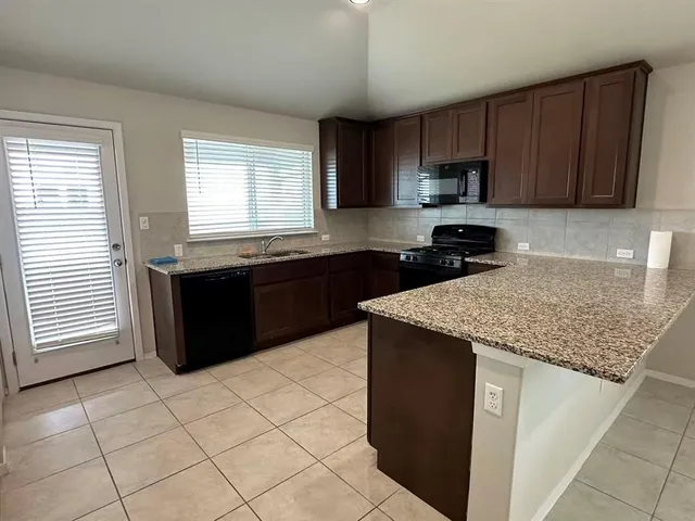 a kitchen with stainless steel appliances granite countertop a sink stove and a refrigerator
