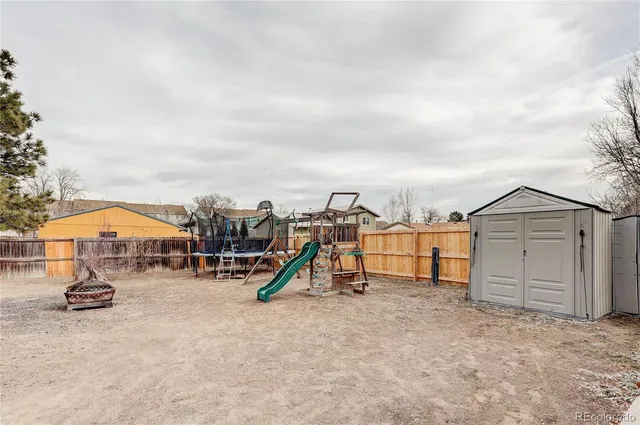 a view of white house with a large tree and wooden fence