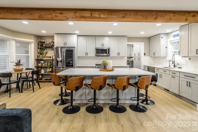 a view of kitchen with dining table wooden floor stainless steel appliances and dining table