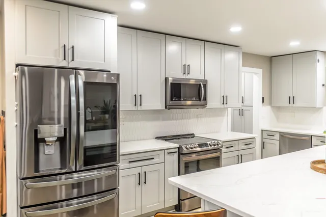 a kitchen with granite countertop a refrigerator stove and microwave