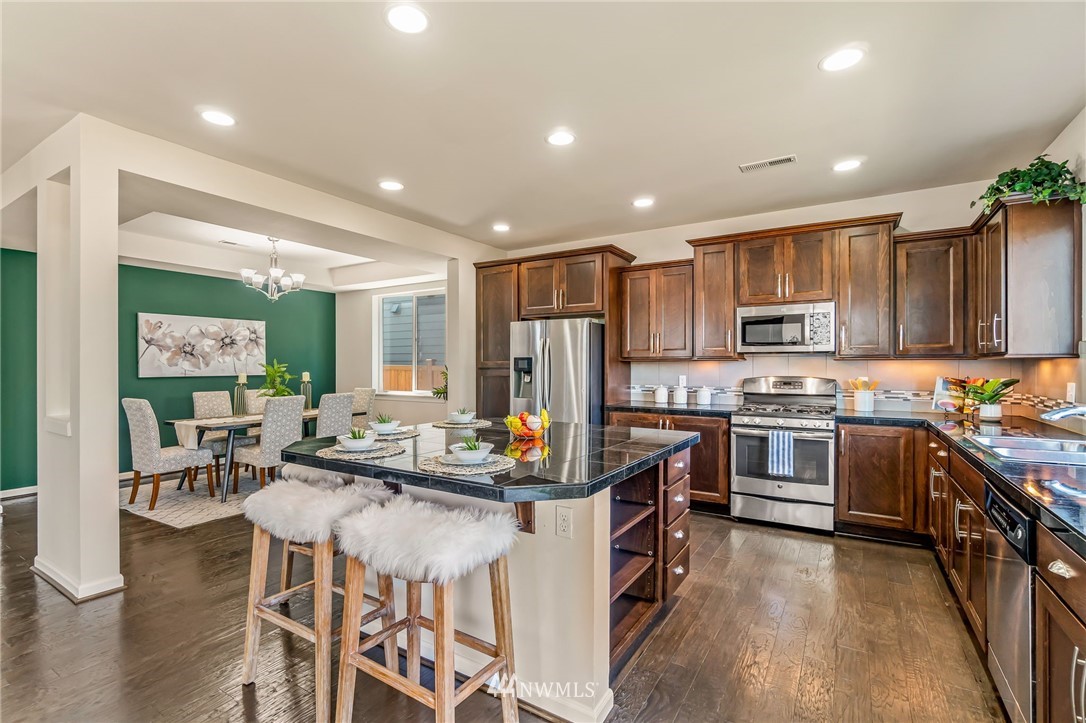 3527 198th Street Southeast Bothell, WA 98012 - Photo 12 of 40 a kitchen with stainless steel appliances granite countertop a stove top oven a sink dishwasher a dining table and chairs with wooden floor