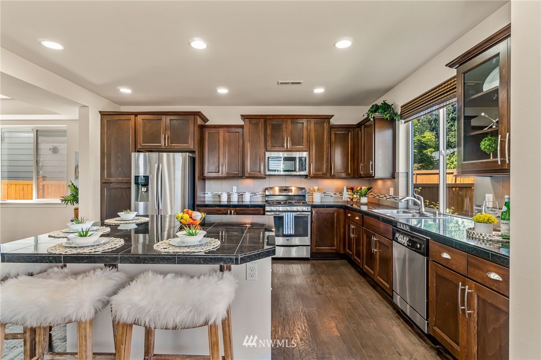 3527 198th Street Southeast Bothell, WA 98012 - Photo 13 of 40 a kitchen with stainless steel appliances granite countertop a stove top oven a sink dishwasher a dining table and chairs