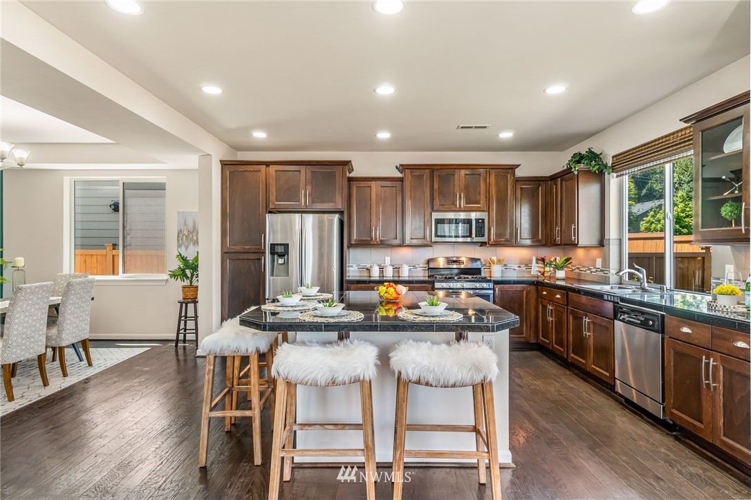3527 198th Street Southeast Bothell, WA 98012 - Photo 16 of 40 a kitchen with kitchen island granite countertop wooden floors and stainless steel appliances