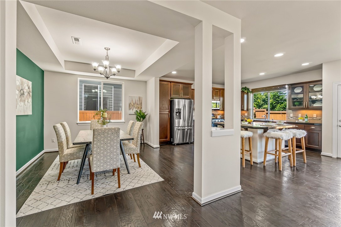 3527 198th Street Southeast Bothell, WA 98012 - Photo 17 of 40 a dining room with wooden floor a chandelier a glass table and chairs
