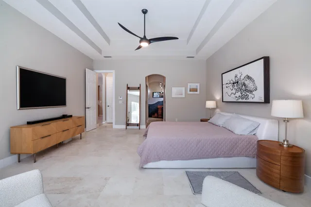 a spacious bedroom with a bed and a flat screen television