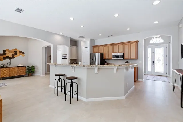 a large white kitchen with stainless steel appliances granite countertop a stove and a refrigerator