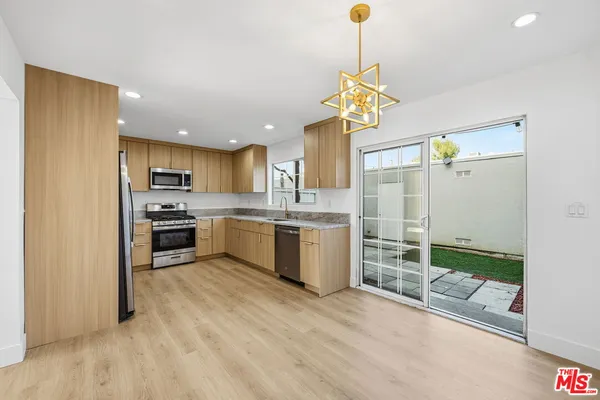 a kitchen with stainless steel appliances granite countertop a sink a stove a refrigerator cabinets and living room view