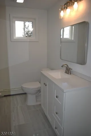 a bathroom with a toilet a sink a mirror and a window