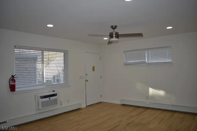 a view of an empty room with a window and wooden floor